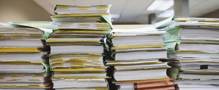 Stacks of documents and files piled high on a desk.