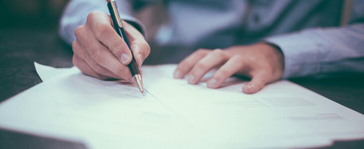 Close-up of hands writing on legal papers with a pen