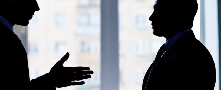 Back lit image of two businessmen arguing